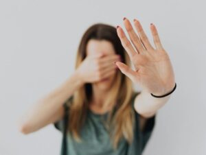 Illustration de l'article "Comment se protéger des relations et environnements toxiques : guide pratique pour un équilibre intérieur". Une femme cache les yeux et montre fermement un signe "stop" avec une main levée.